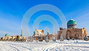 Snow and spruces with blue domes and minarets of muslim Hazrati