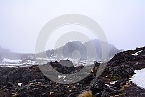 Snow storm building up over lava fields on the slopes of Mt Ruapehu. Patches of snow over Whakapapa Ski Field, Tongariro