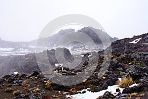 Snow storm building up over lava fields on the slopes of Mt Ruapehu. Patches of snow over Whakapapa Ski Field, Tongariro