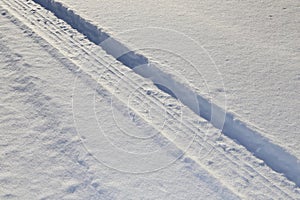 Snow tires imprinted on the road- white texture of real snow for winter back grounds