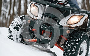 Snow, trees, adventure. Man is riding ATV outdoors in the winter forest