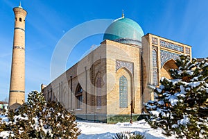 Snow and trees around ornated mosque and minaret of Hazrati Imam complex, religious center of Tashkent