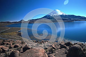 Snow volcano above blue lake