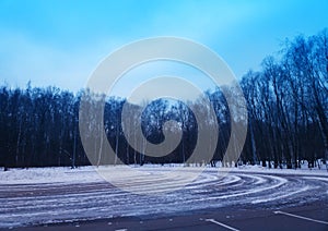 Snow wheel trails at empty winter car parking background