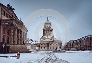 Snow and winter panoramic view of famous Gendarmenmarkt square with Berlin Concert Hall and German Cathedral. Early