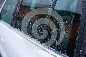 Snow in winter season scraping ice from a windshield . Car side mirror covered with ice . covered car