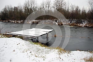 Snow on a wooden pier by a frozen lake