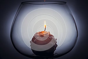 Snowball candle burning inside glass goblet