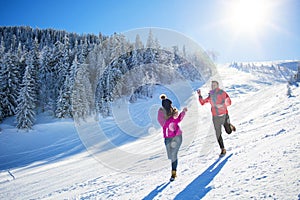 Snowball fight. Winter couple having fun playing in snow outdoors. Young joyful happy multi-racial couple.