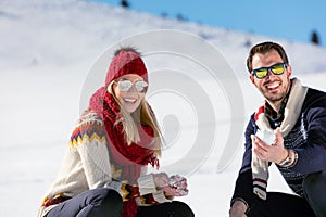 Snowball fight. Winter couple having fun playing in snow outdoors. Young joyful happy multi-racial couple.