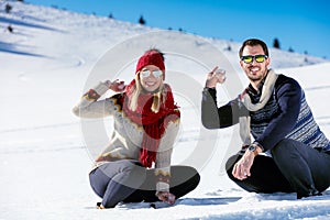 Snowball fight. Winter couple having fun playing in snow outdoors. Young joyful happy multi-racial couple.