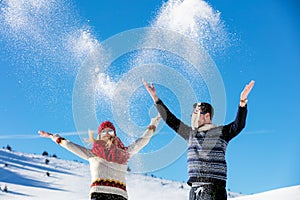 Snowball fight. Winter couple having fun playing in snow outdoors. Young joyful happy multi-racial couple.