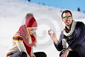 Snowball fight. Winter couple having fun playing in snow outdoors. Young joyful happy multi-racial couple.