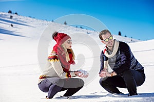 Snowball fight. Winter couple having fun playing in snow outdoors. Young joyful happy multi-racial couple.