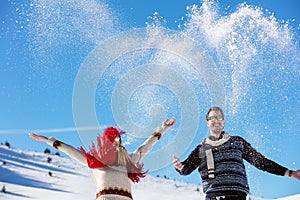 Snowball fight. Winter couple having fun playing in snow outdoors. Young joyful happy multi-racial couple.