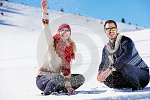 Snowball fight. Winter couple having fun playing in snow outdoors. Young joyful happy multi-racial couple.