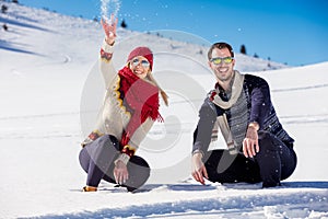 Snowball fight. Winter couple having fun playing in snow outdoors. Young joyful happy multi-racial couple.