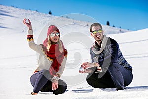 Snowball fight. Winter couple having fun playing in snow outdoors. Young joyful happy multi-racial couple.