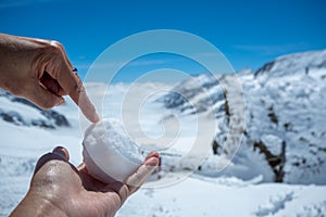 Snowball with two hands on blurred beautiful view of Aletsch Glacier in Jungfraujoch background