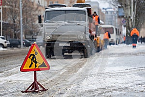 Snowblower clear freezing winter road with snow and ice.Snow-plow remove snow from the city street.Warning road sign photo