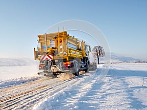 A snowblower clears the road in the snowy fields of Alsace. Movement, sun, purity