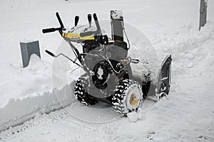 Snowblower parked in a park during a snowfall