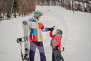 Snowboard instructor teaches a boy to snowboarding. Activities for children in winter. Children`s winter sport