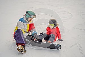 Snowboard instructor teaches a boy to snowboarding. Activities for children in winter. Children`s winter sport