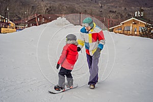 Snowboard instructor teaches a boy to snowboarding. Activities for children in winter. Children`s winter sport