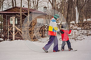 Snowboard instructor teaches a boy to snowboarding. Activities for children in winter. Children`s winter sport