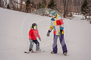 Snowboard instructor teaches a boy to snowboarding. Activities for children in winter. Children`s winter sport