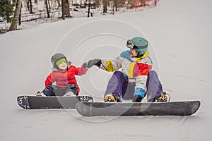 Snowboard instructor teaches a boy to snowboarding. Activities for children in winter. Children`s winter sport