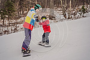 Snowboard instructor teaches a boy to snowboarding. Activities for children in winter. Children`s winter sport