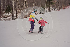 Snowboard instructor teaches a boy to snowboarding. Activities for children in winter. Children`s winter sport