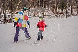 Snowboard instructor teaches a boy to snowboarding. Activities for children in winter. Children`s winter sport