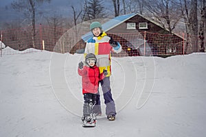 Snowboard instructor teaches a boy to snowboarding. Activities for children in winter. Children`s winter sport