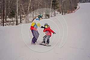 Snowboard instructor teaches a boy to snowboarding. Activities for children in winter. Children`s winter sport