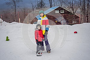 Snowboard instructor teaches a boy to snowboarding. Activities for children in winter. Children`s winter sport