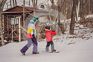 Snowboard instructor teaches a boy to snowboarding wear medical masks due to the COVID-19 coronavirus. Activities for