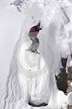 Snowboard jump from a cliff in the powder