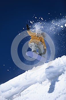 Snowboarder Above Slope With Snow Powder Trailing Behind