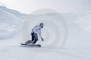 Snowboarder in action on snowy slope in winter sports attire, leaning into a turn.