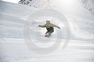 Snowboarder in anorak rides on a snowboard in mountains