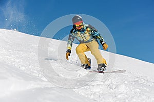 Snowboarder in bright sportswear riding down a mountain slope