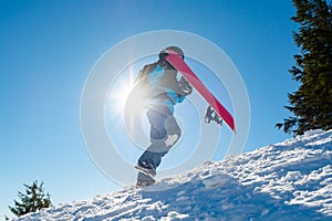 Snowboarder Climbing up with Red Snowboard in the Mountains at Sunny Day. Snowboarding and Winter Sports