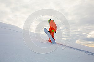 Snowboarder climbing on the top of ski slope