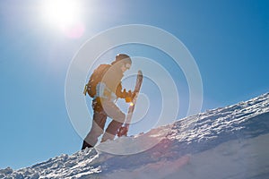 Snowboarder Climbing up with Snowboard in the Mountains at Sunny Day. Snowboarding and Winter Sports