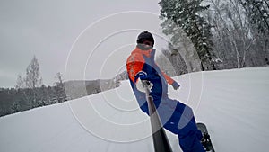 A snowboarder descends from the mountain on a ski track along the forest