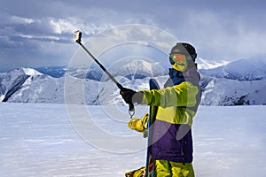 Snowboarder doing selfie on action camera stick