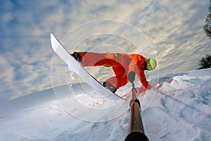 Snowboarder doing a trick and making a selfie